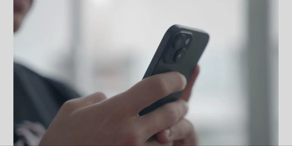 Close-up of a person using an iPhone, representing how to set up parental filter iPhone controls to manage screen time and monitor device usage safely